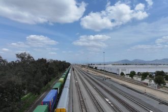 Vista aérea de extensas linhas férreas com trens de carga em uma área aberta.