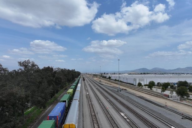 Vista aérea de extensas linhas férreas com trens de carga em uma área aberta.
