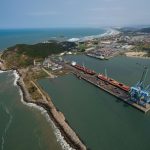 Vista aérea do Porto de Imbituba, com docas, guindastes e embarcações junto à costa brasileira.