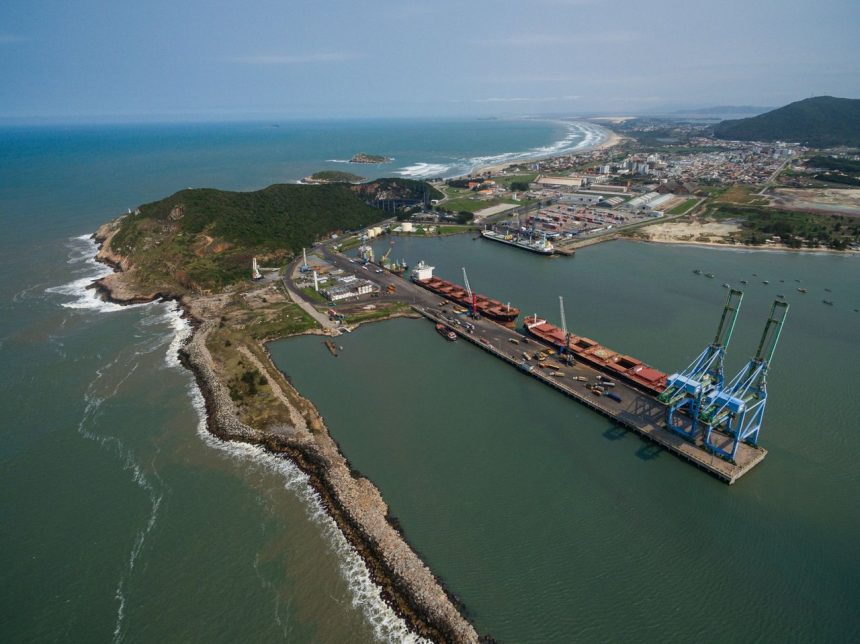 Vista aérea do Porto de Imbituba, com docas, guindastes e embarcações junto à costa brasileira.